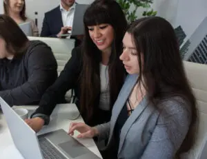 Two women looking at the laptop while working