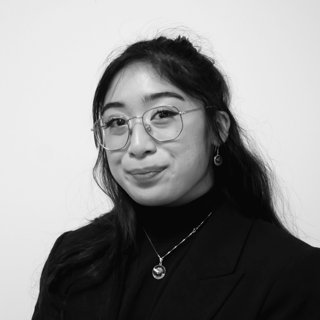 Young woman wearing glasses, smiling confidently.