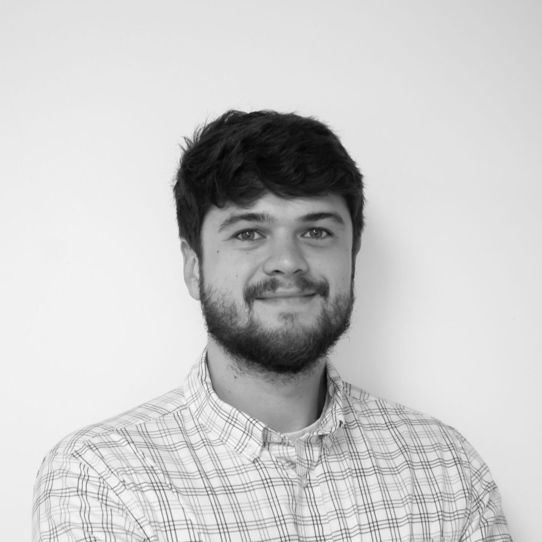 Smiling man with beard in checkered shirt.